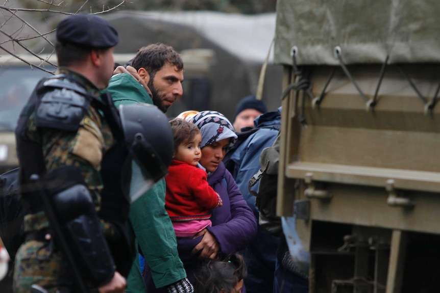 Macedonian soldiers escort asylum seekers who have crossed the border into army trucks.