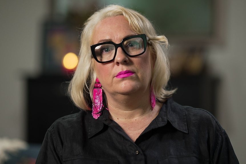 A woman wearing glasses and pink earrings.