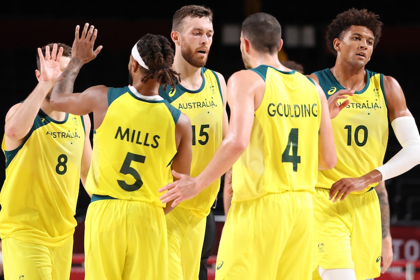 Australia's men's basketball team share high fives in Tokyo.