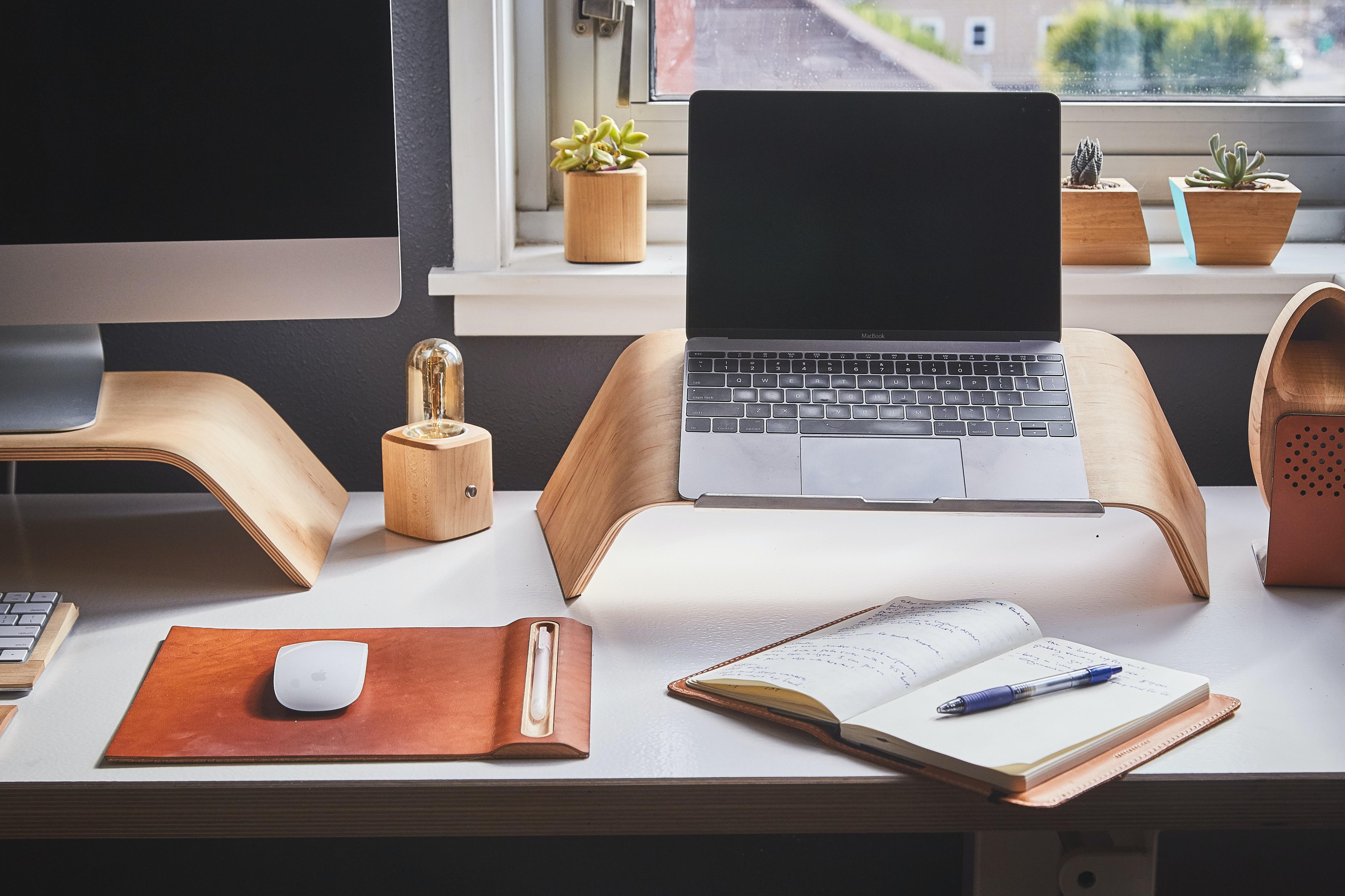 A laptop and notebook on a desk.
