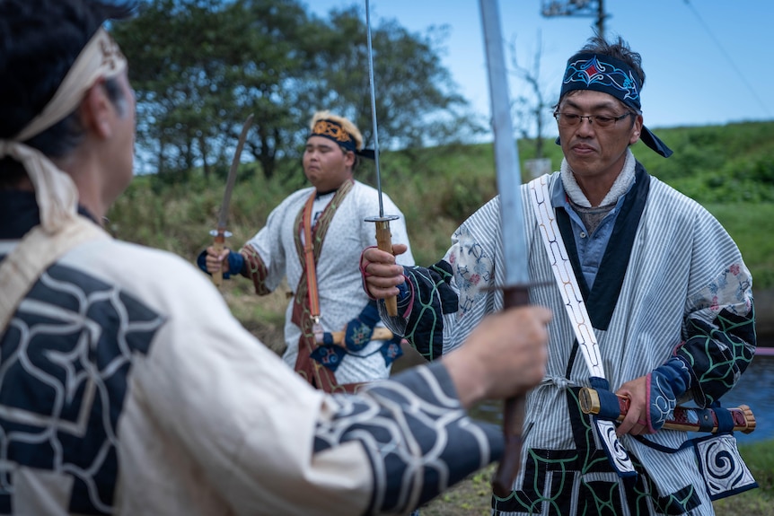 Men with swords stand in a field 