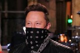 Miley Cyrus, Elon Musk and Cecily Strong on a tv studio stage wearing masks
