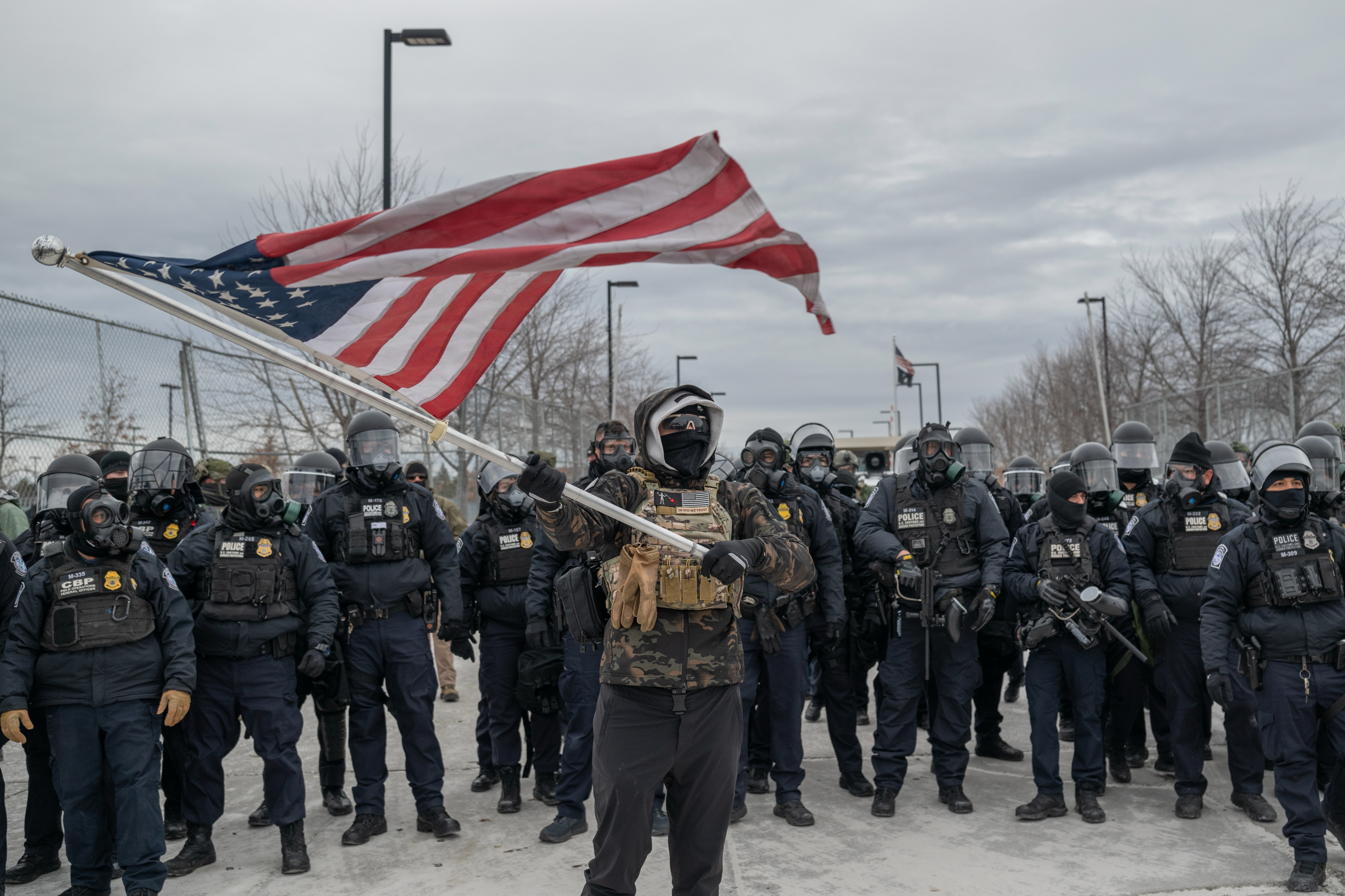 A man waves a flag in front of ICE agents in St Paul, Minnesota.