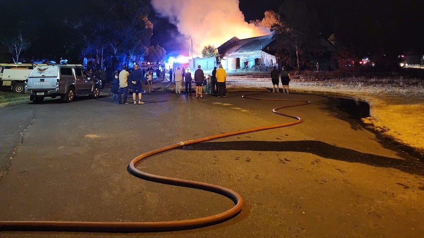 People watching the fire, with a hose in front of them