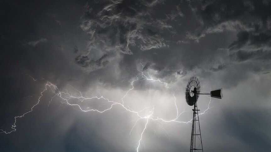 Windmill against steel grey lightning-filled sky