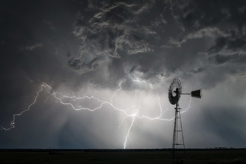 Windmill against steel grey lightning-filled sky