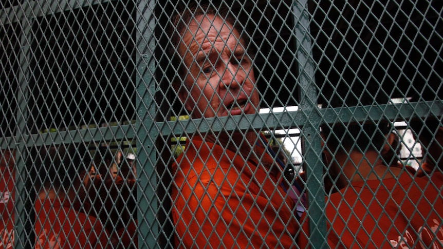 James Ricketson sits behind a cage in a prison truck