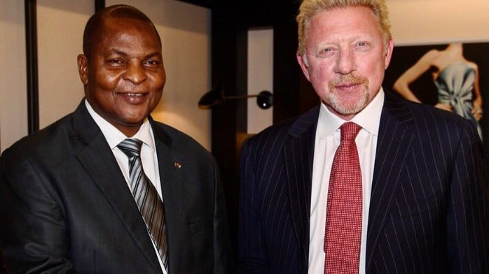 Mr Touadera (left) shakes hands with Becker. Both are dressed in suits, smiling and looking at the camera