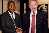 Mr Touadera (left) shakes hands with Becker. Both are dressed in suits, smiling and looking at the camera