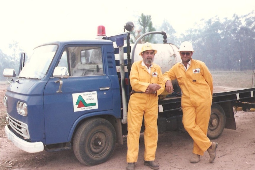 An historic photo of a two men next to an old fire truck 
