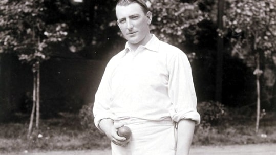A black and white photo of Warwick Armstrong in whites and holding a cricket ball, signed "yours sincerely, Warwick Armstrong"