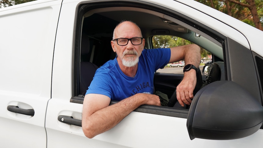 Man in car driver's seat of van.