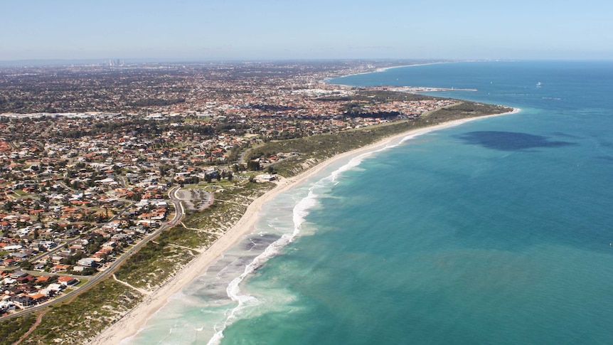 Aerial shot of a coastline with buildings and development along the side.