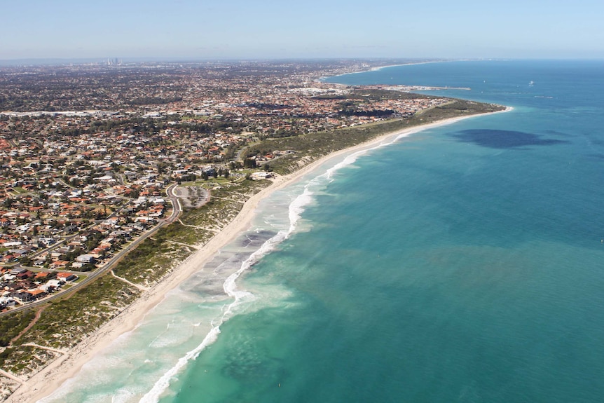 Aerial shot of a coastline with buildings and development along the side.