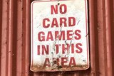 A sign on a tin shed says 'No card games in this area'
