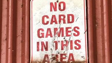 A sign on a tin shed says 'No card games in this area'