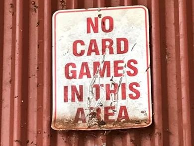 A sign on a tin shed says 'No card games in this area'