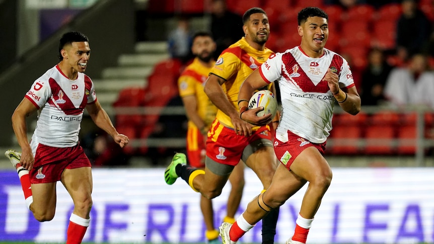Tonga's Isaiya Katoa runs away from Papua New Guinea defenders to score a try at the Rugby League World Cup.