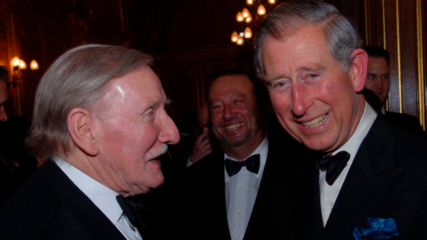 Prince Charles smiles to camera as actor Leslie Philips looks at him. 