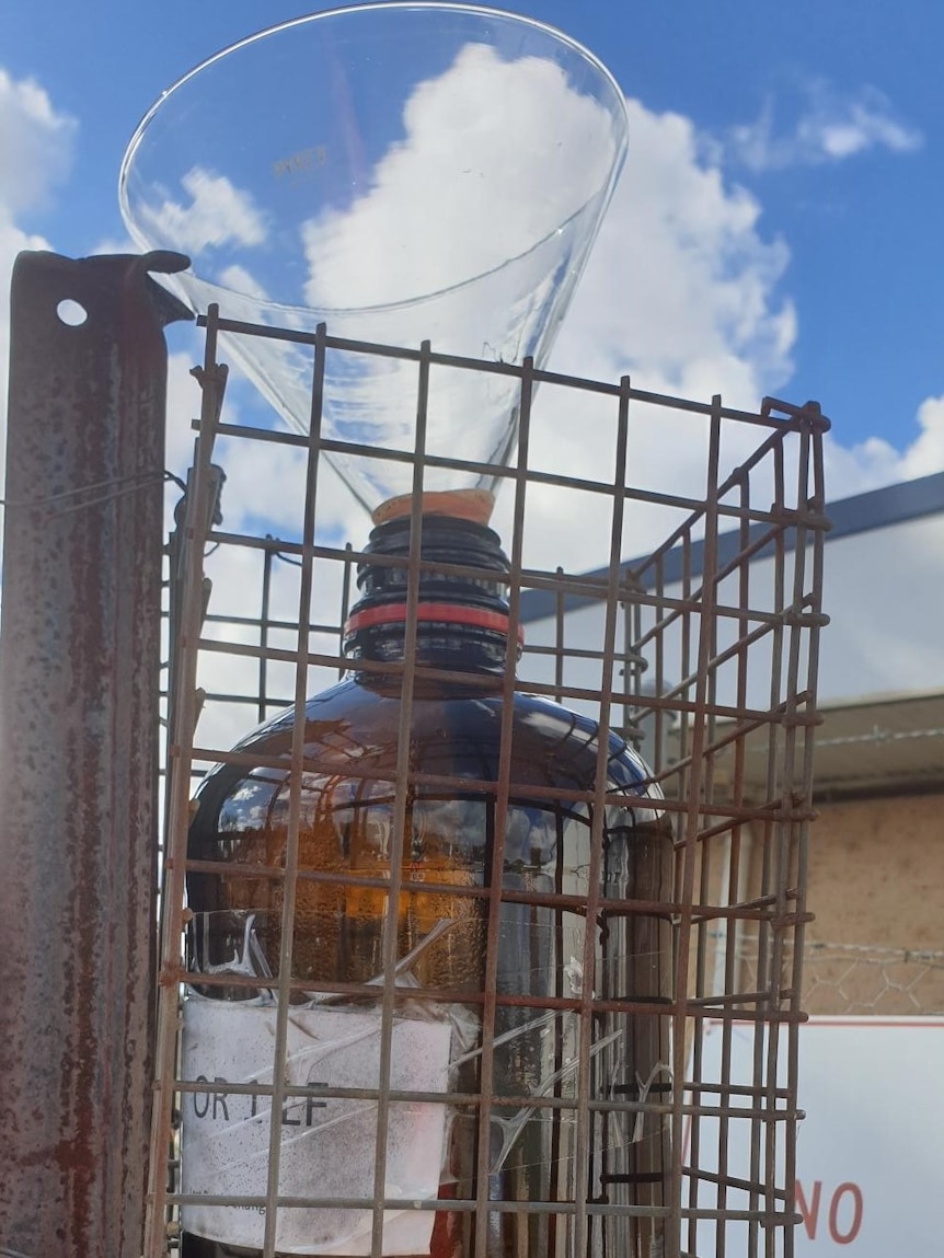 DIY dust monitor is glass bottle with a funnel held in a wire cage