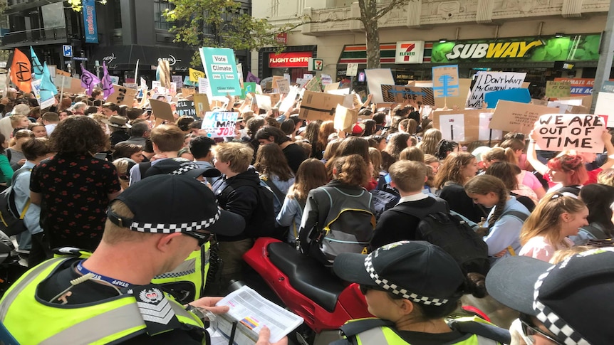 Big crowds of protesters hold up signs as police watch on