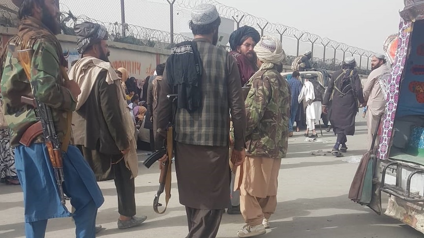 The photo appears to show Taliban militants near a checkpoint at Kabul Airport