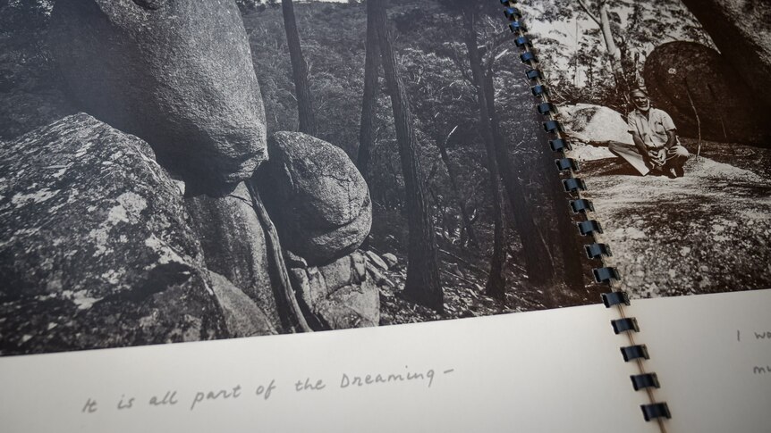 Book open with black and white photos of rock formations and handwritten text "It is all a part of the Dreaming"