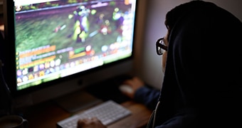 A young man plays a game on his computer.