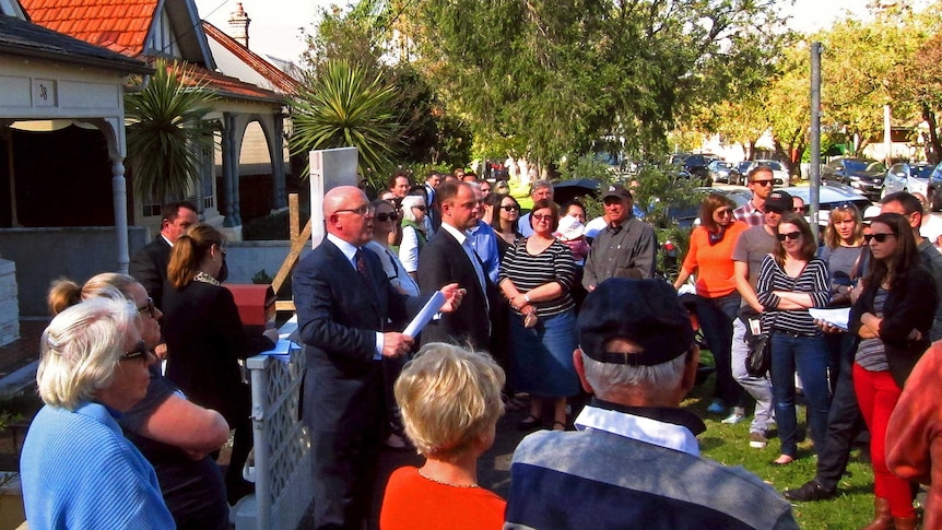 A Sydney auctioneer yells out bids in front of a crowd of potential buyers in this August 24, 2013 file picture.