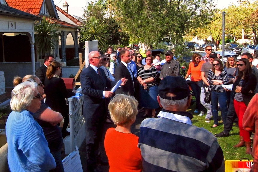 A Sydney auctioneer yells out bids in front of a crowd of potential buyers in this August 24, 2013 file picture.