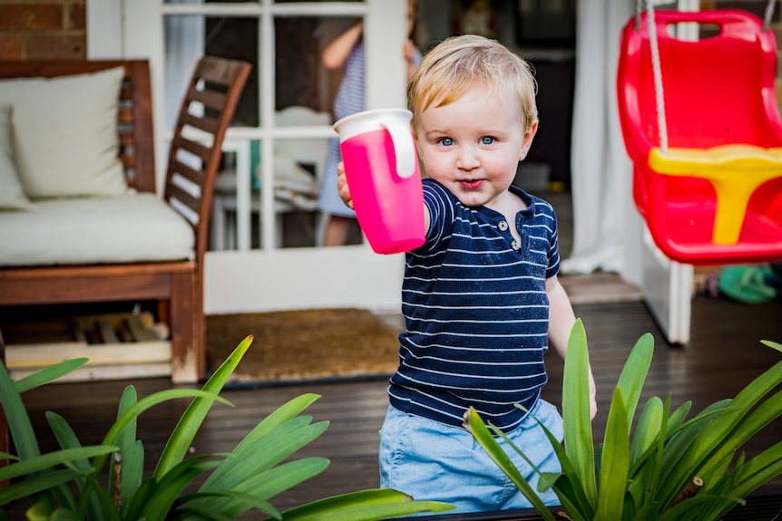 Mathew Cantali playfully brandishing a pink cup and smilling towards the camera.