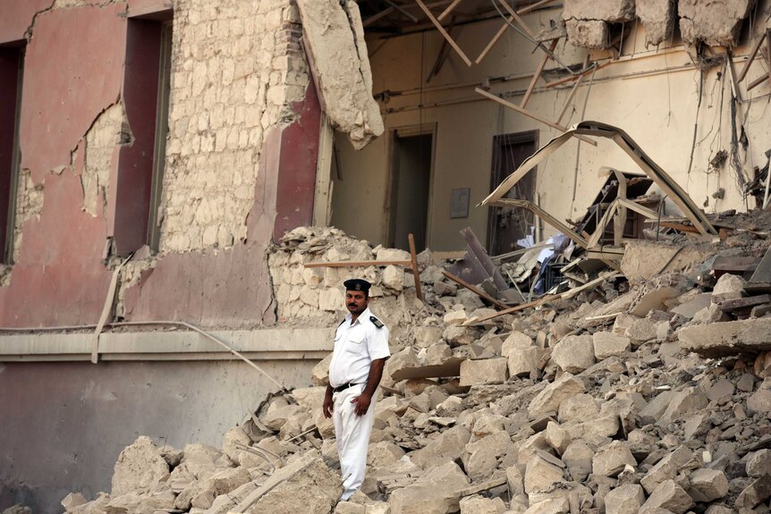 An Egyptian policeman stands in the rubble at the site of the Italian consulate bomb explosion