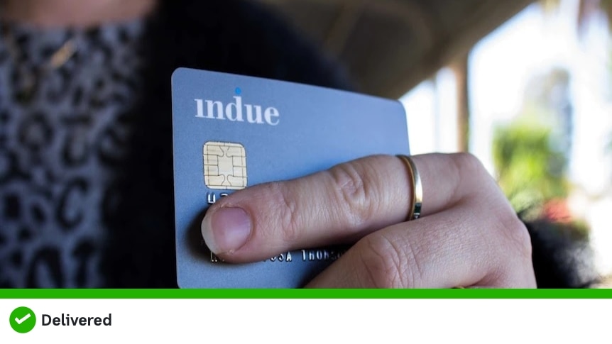 A close up of a woman's hand holding a blue debit card labelled "Indue"