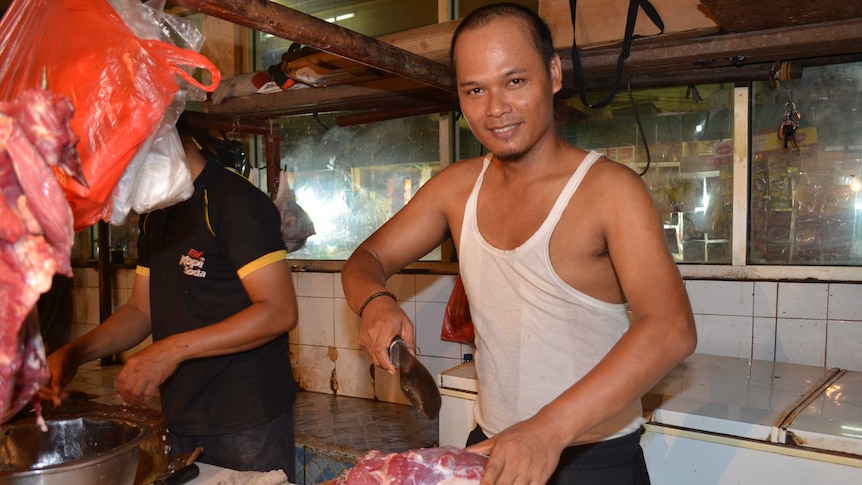 A butcher in a wet meat market in Indonesia prepares beef for local consumers.