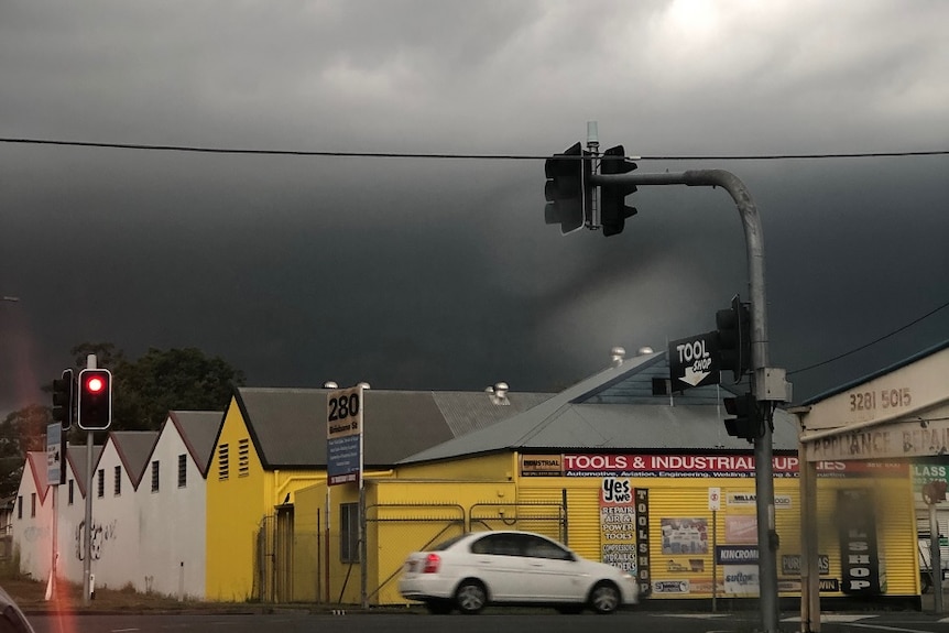 Ominous clouds over Yamanto in Ipswich as cars drive on the streets.