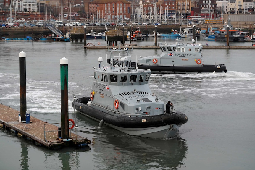 British Coastal Patrol boats sit in the harbour where buildings can be seen in the background.