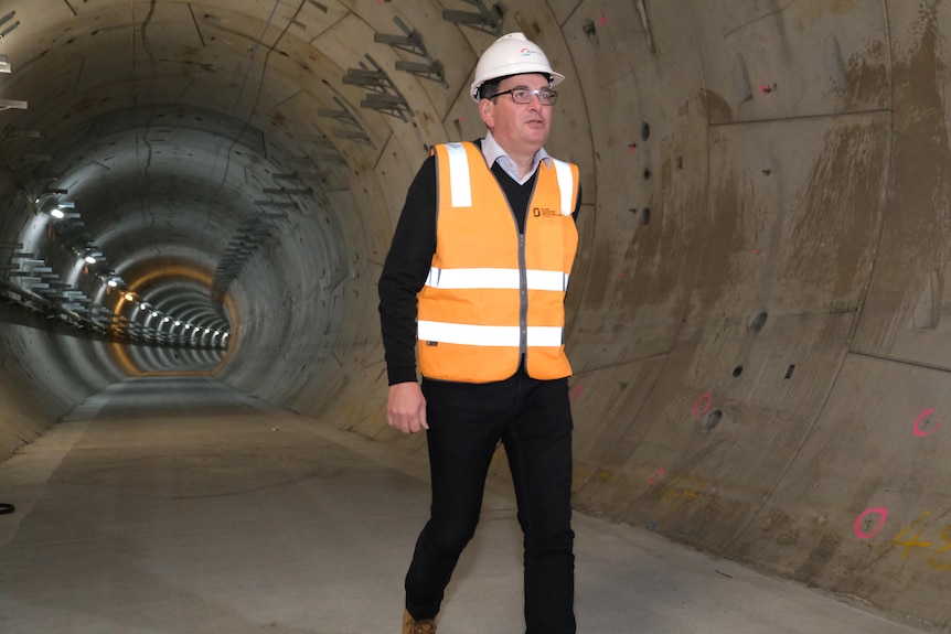 Daniel Andrews walks through a tunnel wearing a hardhat and fluro vest.
