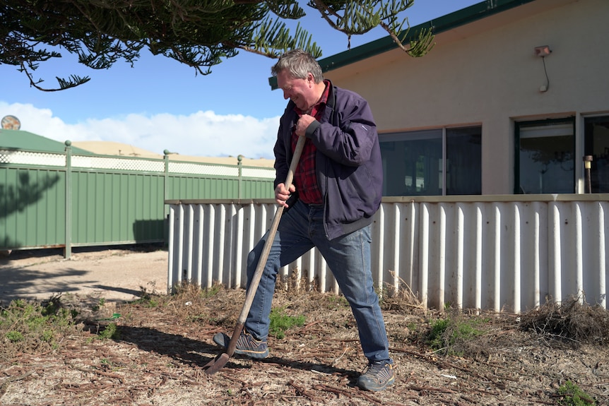 A man in a blue jacket digs with a shovel.