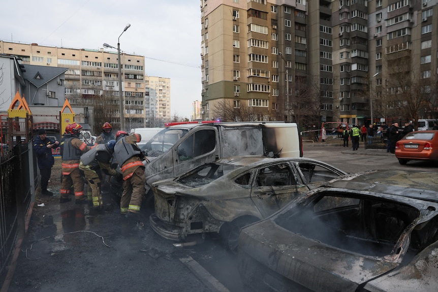 Emergency workers attend to burnt cars after a missile strike in Kyiv.