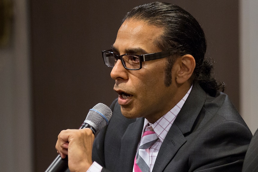 Gurpatwant Singh Pannum holds a microphone and speaks.