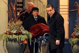 Police use a stretcher to remove a body covered by red material from the home of Barry and Honey Sherman.