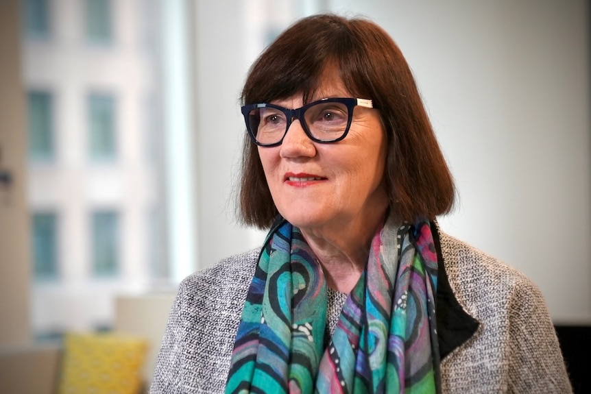 A woman with dark hair and dark glasses looks off-camera.