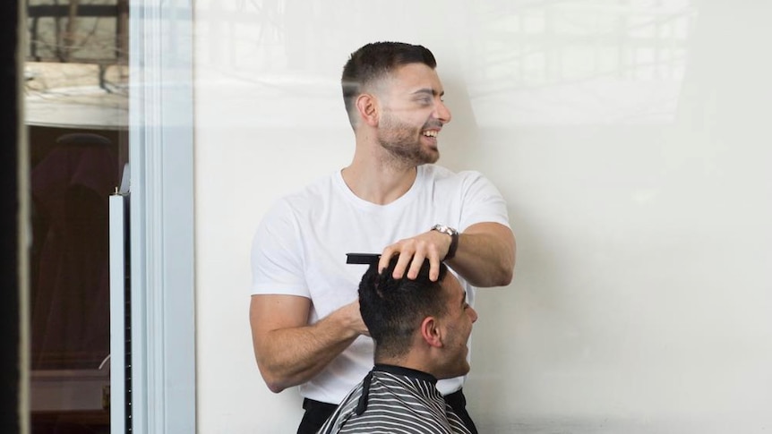 A barber cuts a man's hair. 