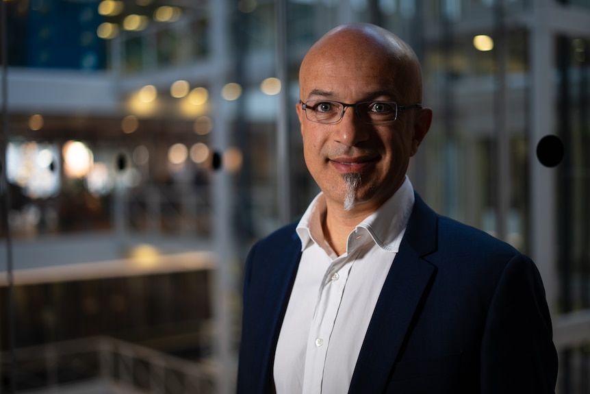 A bald man with glasses and some facial hair poses for the camera.