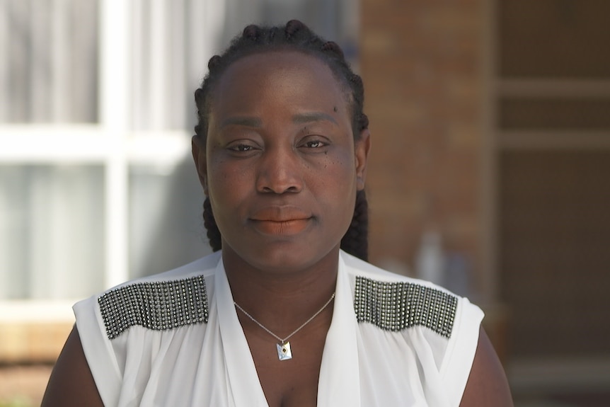 Woman wearing a white shirt sitting outside a house.