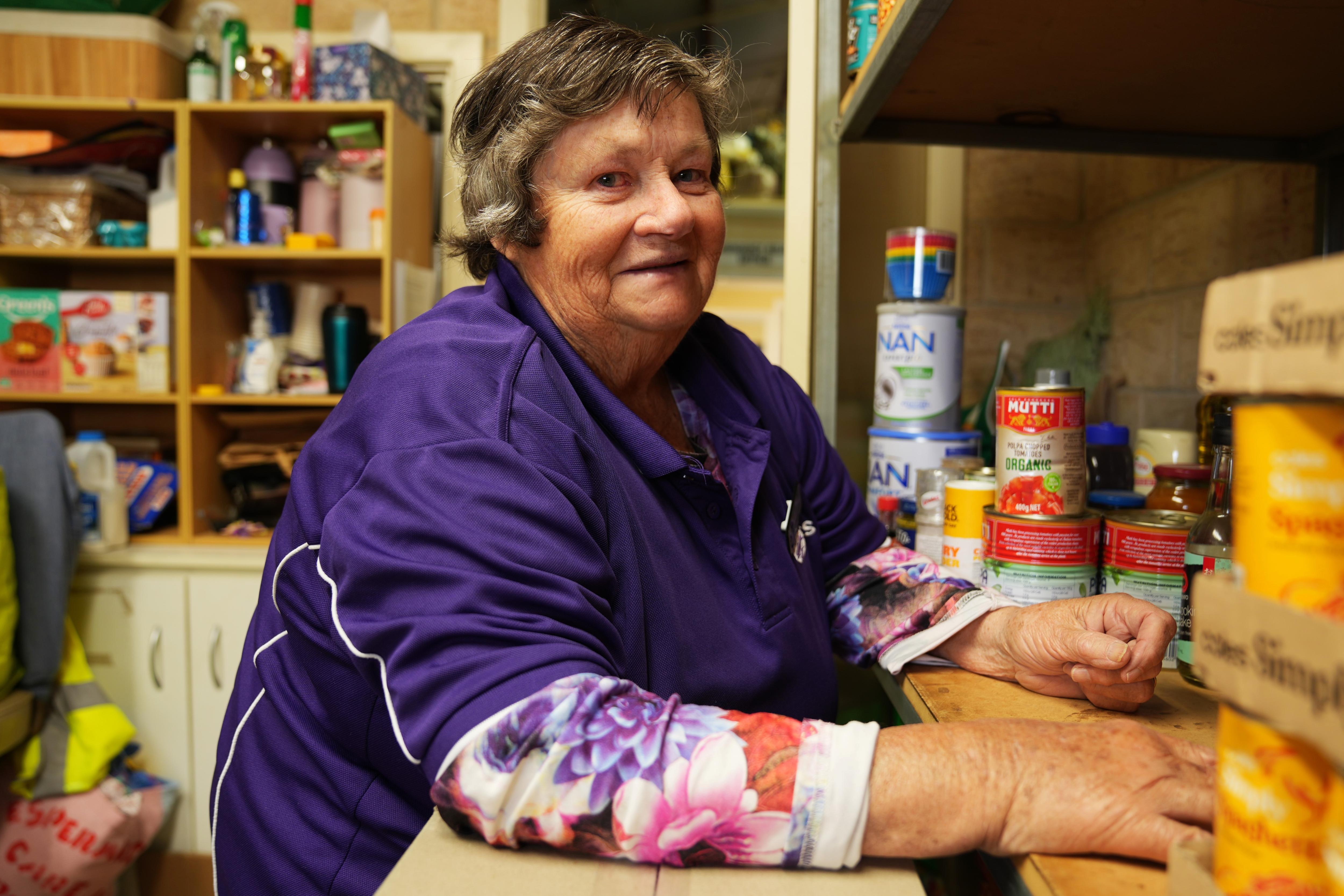 She stands in a pantry in a purple tshirt