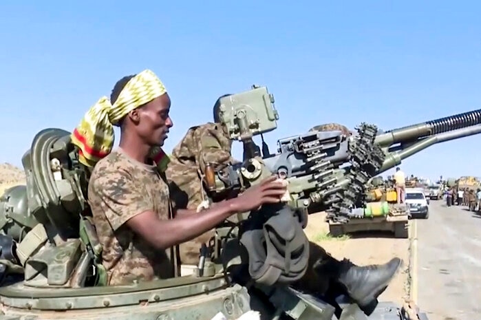 On a bright day, you view a soldier in a gun turret on a tank on a desert road.