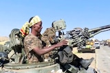 On a bright day, you view a soldier in a gun turret on a tank on a desert road.