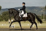 Christine Crawford and black horse competing in dressage.