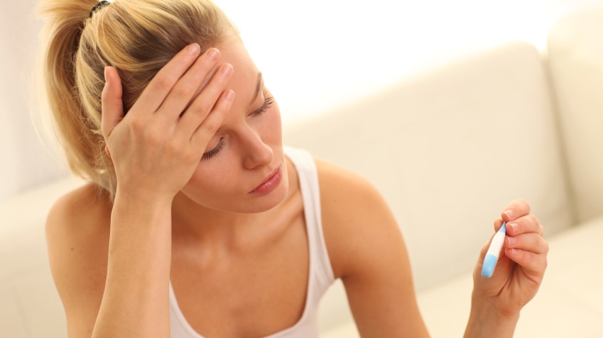 A woman with a fever looking at a thermometer